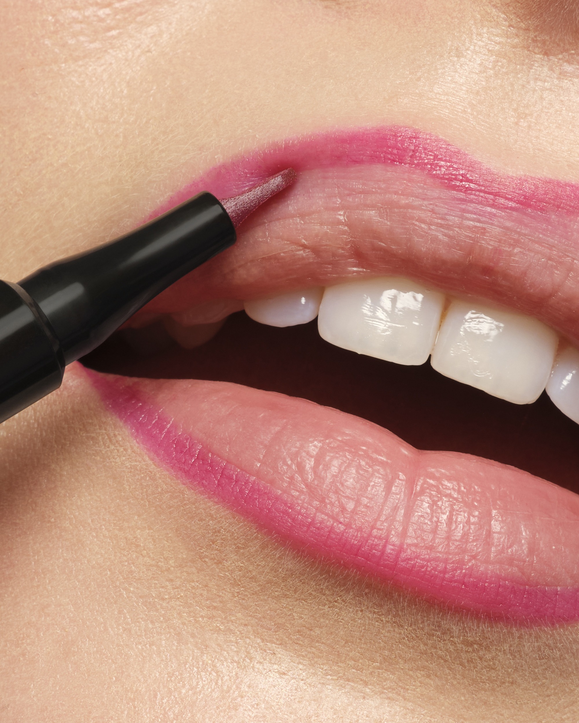 Close-up of pink lipstick being applied to the lips with a wand applicator near the lower lip.